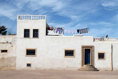 Whitewashed mediterranean house with rooftop laundry and blue door under clear sky