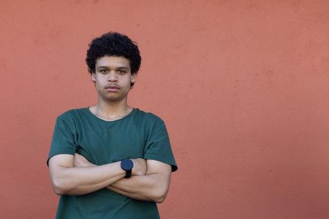 Confident african young man standing with arms crossed against terracotta wall