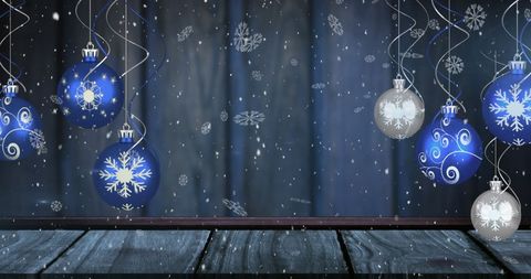 Festive Snowfall with Hanging Baubles Against a Blue Background