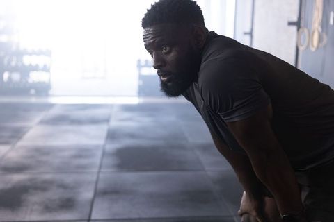 African american athlete catching breath bending forward after intense gym training