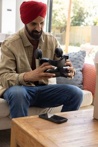 Indian man exploring virtual reality headset in modern living room