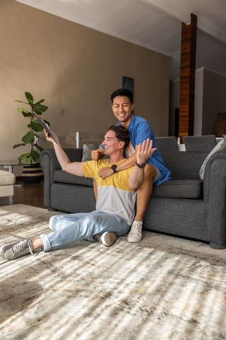 Sunlit living room couple cuddling on sofa with tablet, joyful partners embracing