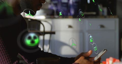 Man holding smartphone tapping augmented reality sustainability icons at kitchen table