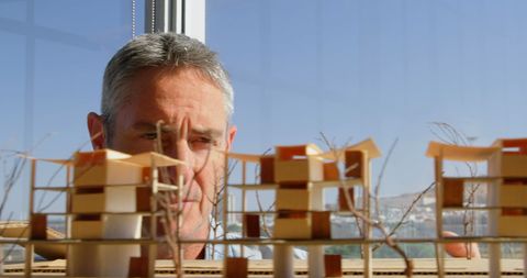 Architect Examining Intricate Building Model in Office