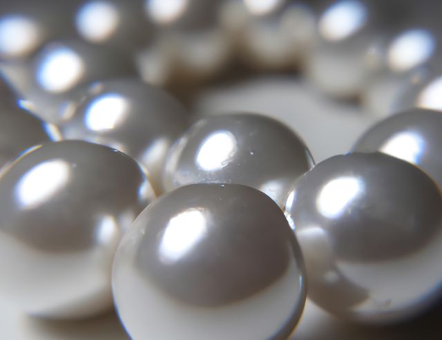 Detailed close-up view of shiny white pearls. Ideal for use in jewelry advertisements, luxury branding, or as a decorative element in fashion and beauty projects. Captures the elegance and glamour of natural pearls, perfect for appealing to audiences interested in high-end fashion and accessories.