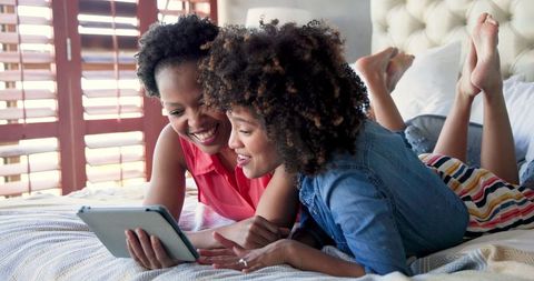 Friends Relaxing at Home Using Tablet in Bedroom