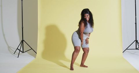 Woman in Athletic Wear Posing on Yellow Backdrop