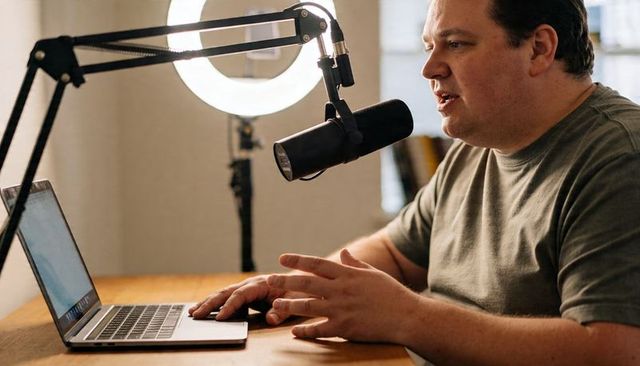 Podcaster Speaking and Gesturing While Recording with Microphone, Laptop and Ring Light