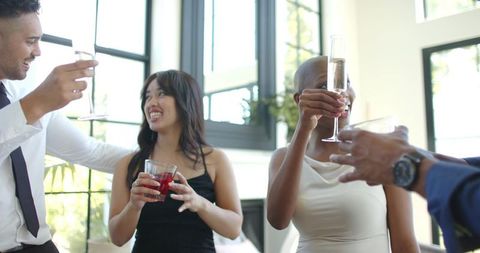 Group raising champagne flutes and toasting in bright modern lounge celebrating together