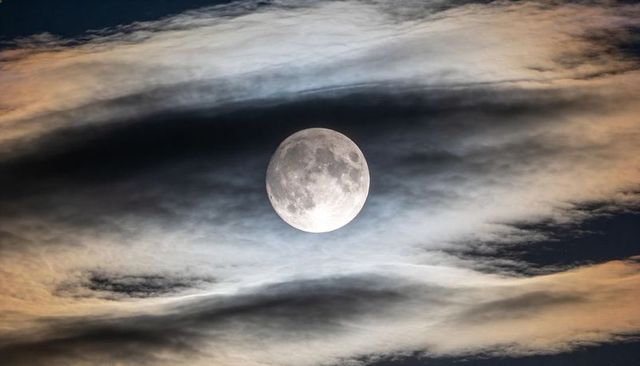 Glowing Full Moon Framed by Cloud Halo Over Midnight Sky with Visible Craters and Maria