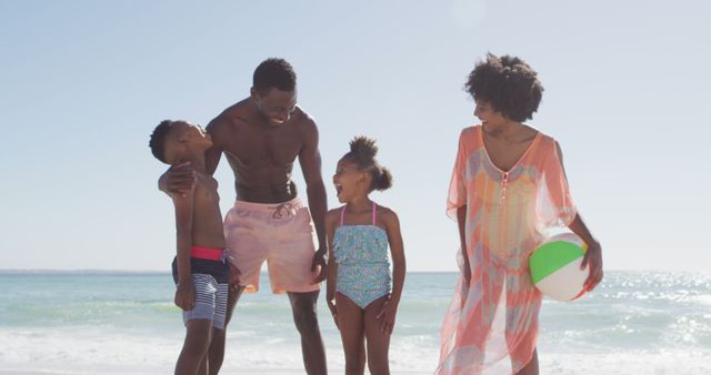 Portrait of smiling african american family embracing on sunny beach. healthy, active family beach holiday.