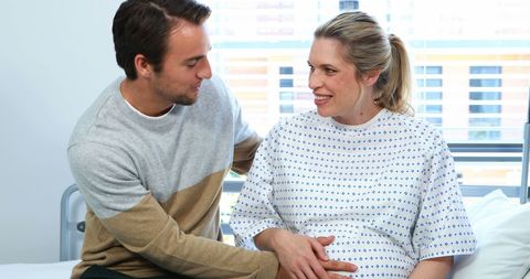 Expectant Couple Sharing Tender Moment in Hospital Ward