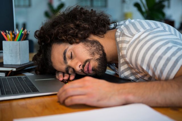 Overworked graphic designer sleeping on his desk - Download Free Stock Photos Pikwizard.com