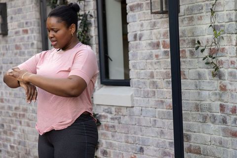 Checking smartwatch after outdoor workout by urban gray brick wall