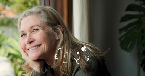 Smiling senior woman resting by window with currency symbols for retirement planning