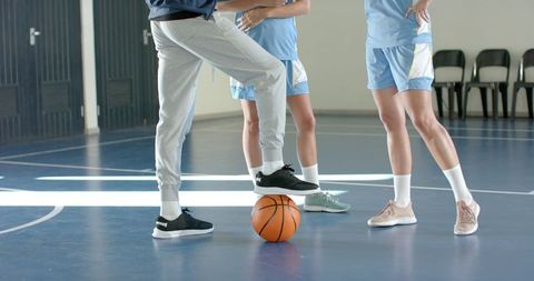 Coach Showing Strategy to Players with Basketball on Indoor Court