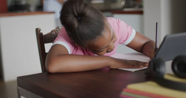 Young Girl Doing Homework at Table Focusing on Digital Tablet - Download Free Stock Images Pikwizard.com