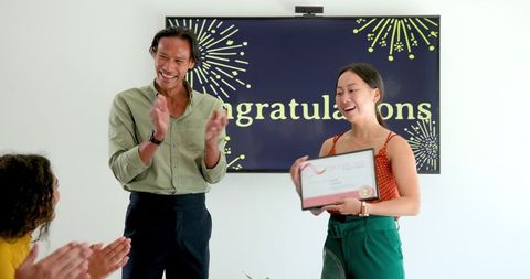 Diverse team celebrating employee achievement with award and applause