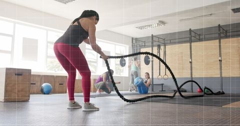 Woman engaged in battle rope workout at gym with graph overlay