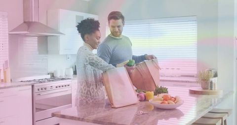 Multicultural couple unpacking groceries in modern kitchen