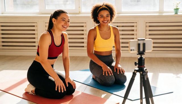 Two Women Recording Yoga Session on Smartphone Tripod in Bright Sunlit Studio