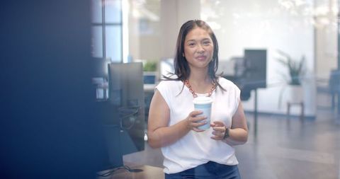Confident woman enjoying coffee break in modern office setting