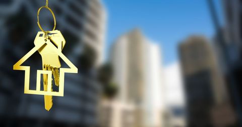 Golden House Key Dangling Against Urban Cityscape