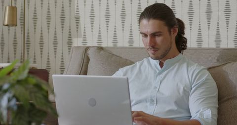 Man deep in thought using laptop in casual home environment