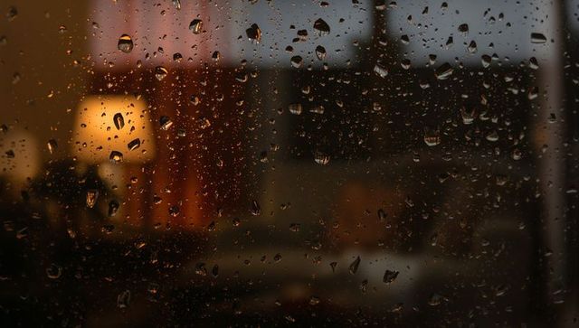 Raindrops on window with cozy indoor scene at night