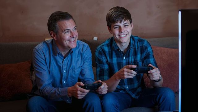Father and teenage son bonding over video games at home