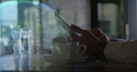 Tapping smartphone at cafe with globe overlay representing global connectivity and remote work