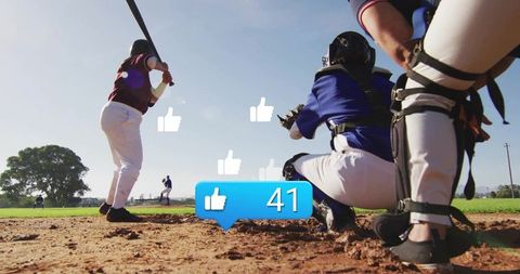 Youth baseball batter facing catcher with social media likes overlay on sunny field
