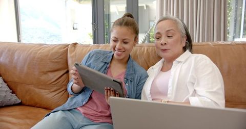 Asian Grandmother and Granddaughter Using Tablet and Laptop at Home