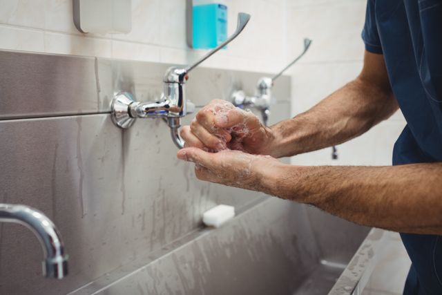 Mid section of male surgeon washing his hands at the hospital