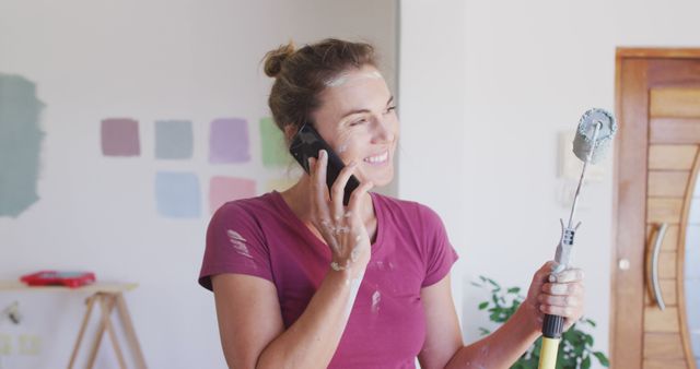 Woman Smiling While Talking on Phone and Holding Paint Roller - Download Free Stock Images Pikwizard.com