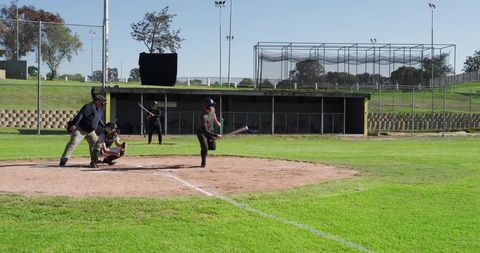 Diverse youth baseball players swinging at plate during sunny community ballpark game