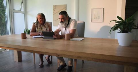 Senior Couple Analyzing Finances at Home Using Tablet