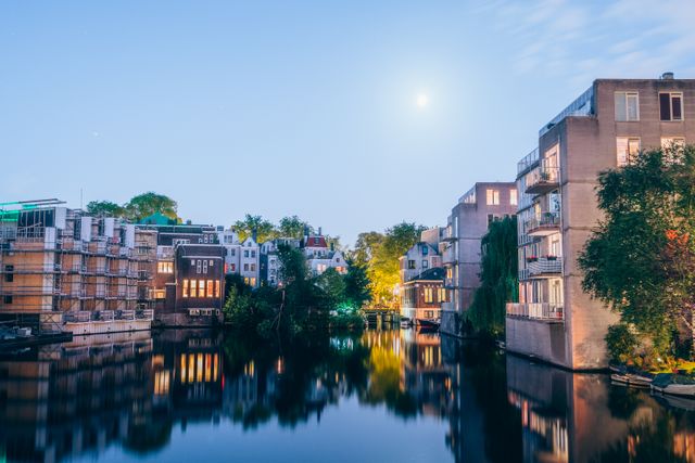 Beautiful urban landscape showcasing waterfront buildings reflected in calm river at twilight. Ideal for travel websites, real estate promotions, city guides, and architectural publications.