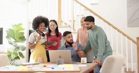 Diverse Team Collaborates Around Laptop and Tablet in Modern Office