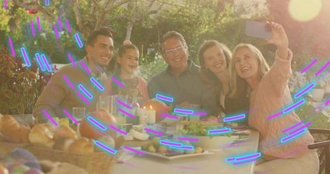 Multigenerational family taking selfie at golden hour backyard dinner with candlelight