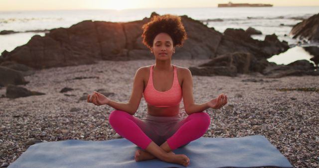 Woman practicing meditation and yoga on a beach during sunset, focusing on calmness and tranquility. Ideal for use in wellness, fitness, meditation, and self-care content. Perfect for promoting relaxation, mental health, and the beauty of outdoor physical activities in nature.