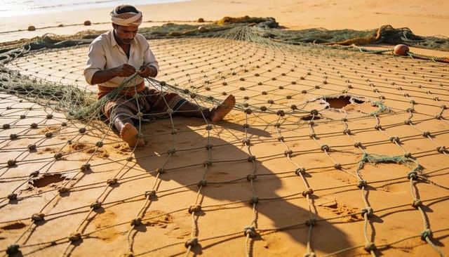 Fisherman mending large fishing net on sandy beach at sunrise repairing traditional gear