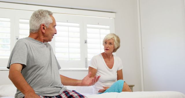 Senior Couple in Pajamas Having Serious Conversation on Bed - Download Free Stock Images Pikwizard.com