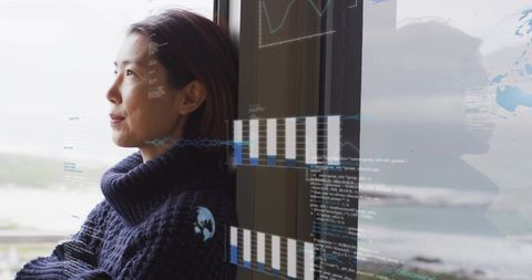 Coastal data analyst gazing through window with holographic charts and global visualizations