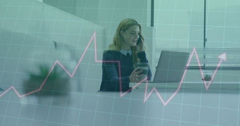 Businesswoman talking on phone while working on laptop with rising data chart overlay