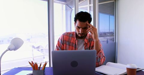 Focused Young Man Working on Laptop in Bright Office Setting