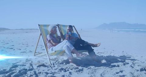 Senior Couple Relaxing on Beach with Sunbeds and Drinks