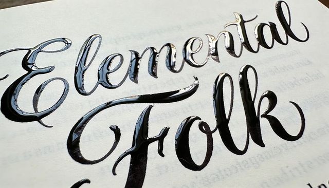Glossy black raised calligraphy lettering with embossed varnish on paper closeup