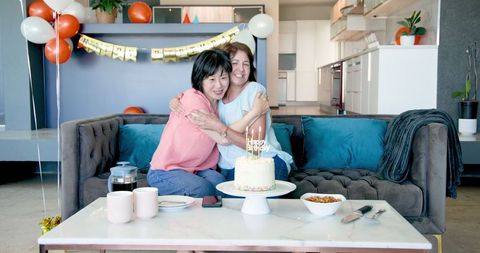 Senior Friends Celebrating Birthday With Cake in Cozy Living Room