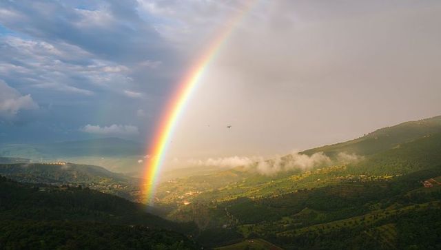 Arching rainbow over terraced valleys and scenic landscape